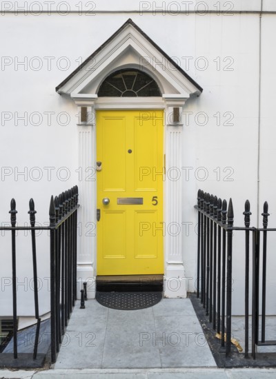 Bright yellow front door with house number five and neoclassical triangular gable, Palladian-style
