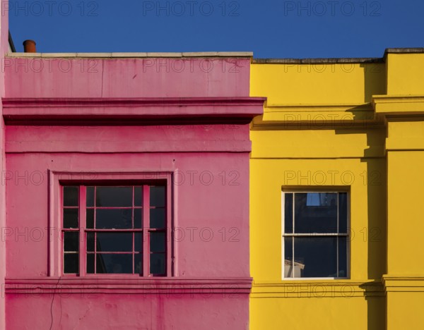 Colourful building facades in pink and yellow, blue sky, Portobello Road, Notting Hill, London,