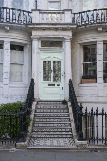 House entrance with mint green door, black and white staircase and decorative wrought iron