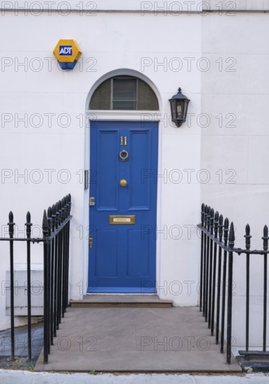Blue door with house number 11 flanked by a lantern and a security sign, surrounded by a wrought