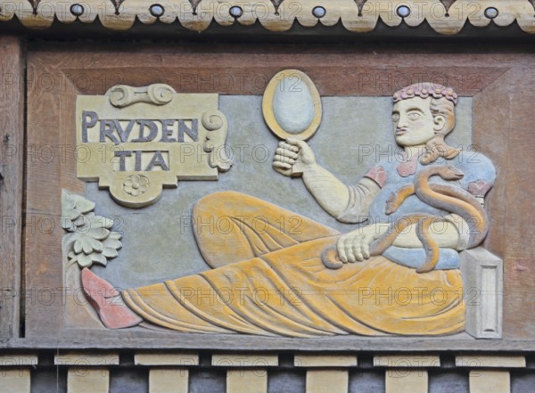 Allegorical wood carving with figure of Prudentia, symbol of prudence and reason, mirror, snake