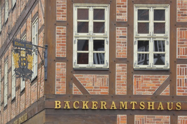 Nose plate with golden year on a brick house, half-timbered house, house facade, window, wrought