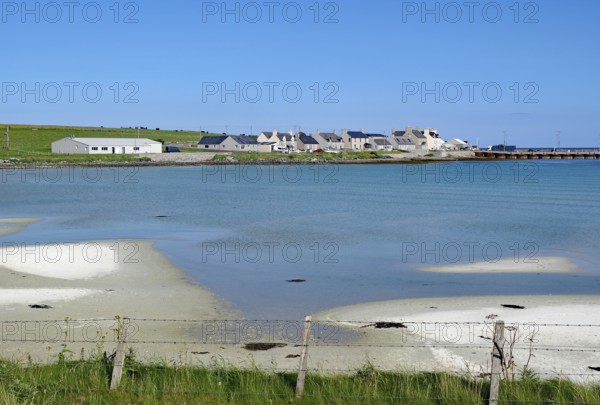 Coastline with sand and village by the shimmering blue sea, Pierowal, Westray, Orkney Islands,