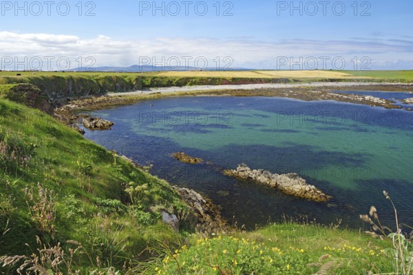 Picturesque bay with clear water, surrounded by green cliffs and wide skies, Pierowal, Westray,