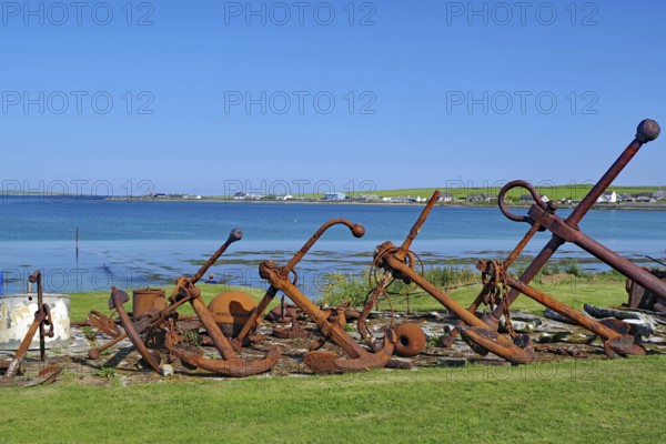 Rusty anchors in a meadow on the coast with sea in the background, Pierowal, Westray, Orkney
