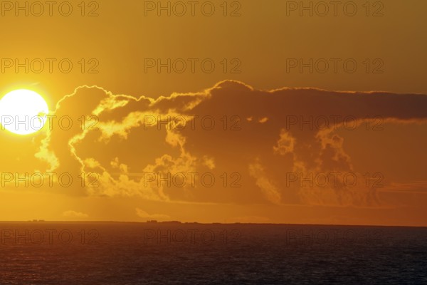 Sunset over the sea with bright sun and dramatic clouds, crossing between Orkney and Shetland
