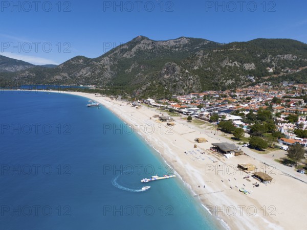 Aerial view of a long sandy beach with neighbouring town and mountainous background, aerial view,