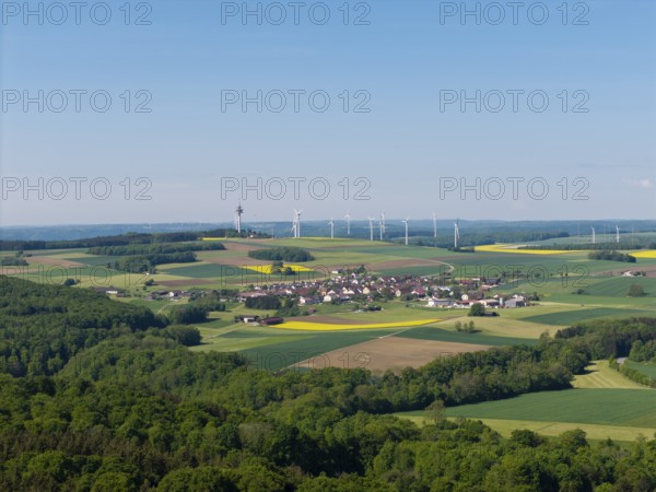 A small village surrounded by fields and wind turbines on green hills, near Böhmenkirch, Swabian