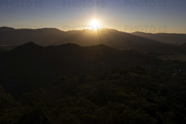The sun sets behind the mountains on the Mediterranean island of Sardinia, Monte Nai, Costa Rei,