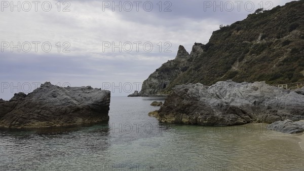 Barren rocky landscape on the coast under a cloudy sky with calm sea, Ricadi, Capo Vaticano