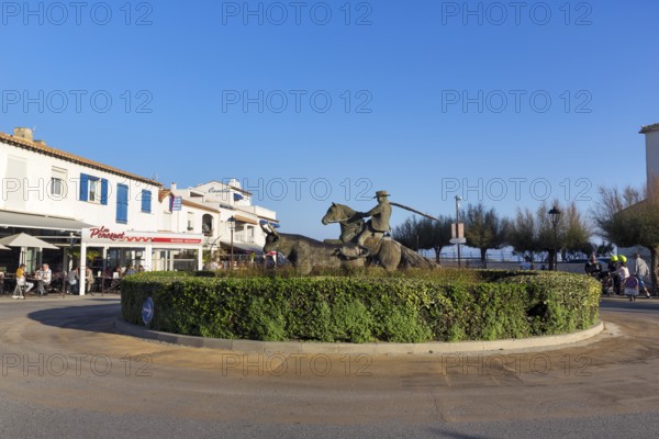 Roundabout with sculptures, cattle herder, guardian of the Camargue on a horse, next to a bull,