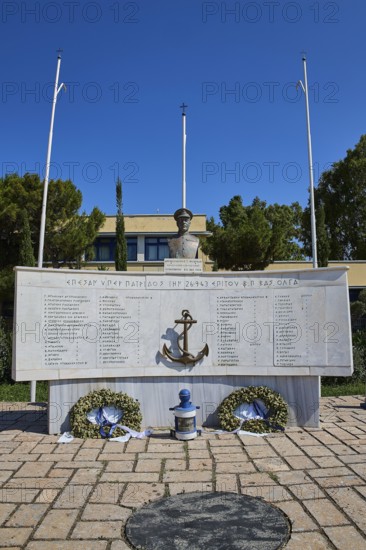 An open-air monument with bust and anchor, accompanied by plaques with inscriptions and wreaths,