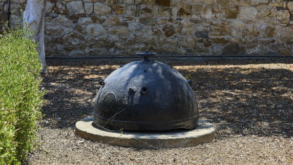 Bellini's Tower, Museum, An old black mine sits on a concrete foundation in front of a stone wall,
