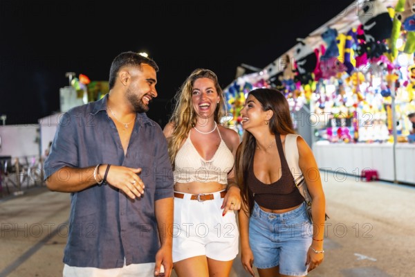 Group of three young friends laughing and walking together in an amusement park, enjoying the