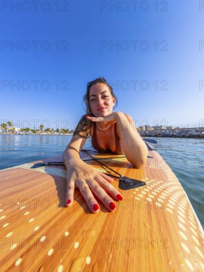 Young woman lying on a paddle board, soaking up the sun and enjoying the warm summer day while