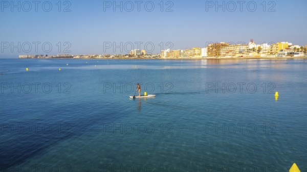 Calm waters and clear skies set the scene for a serene paddle boarding experience near a coastal
