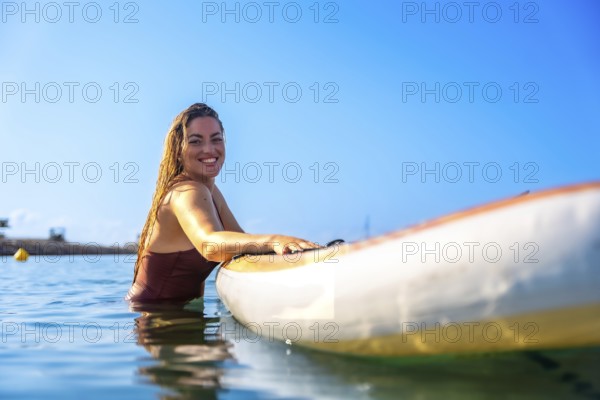 Woman enjoying paddle surfing in clear blue water, showcasing a joyful summer experience under a