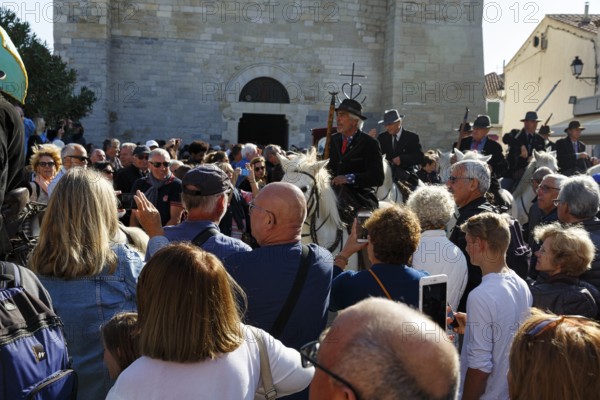 Crowd in front of the church, guardians of the Camargue, traditional shepherds, rider on Camargue