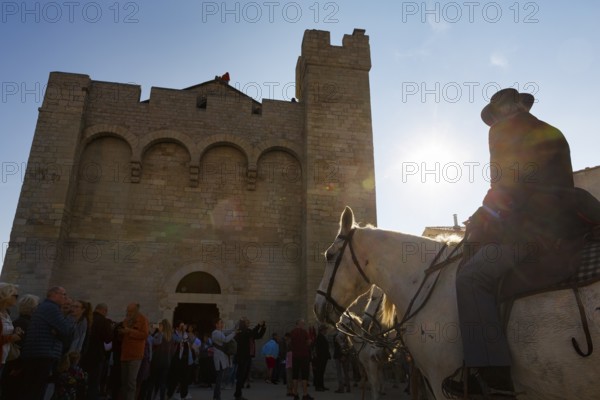 Guardian of the Camargue, rider on Camargue horse in front of the church, sunbeams, backlight,