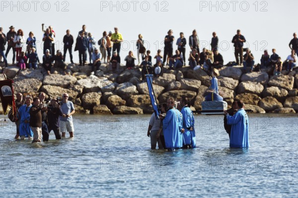 Pilgrimage, procession by the sea, pilgrims walking through water, statue of the Virgin Mary, crowd