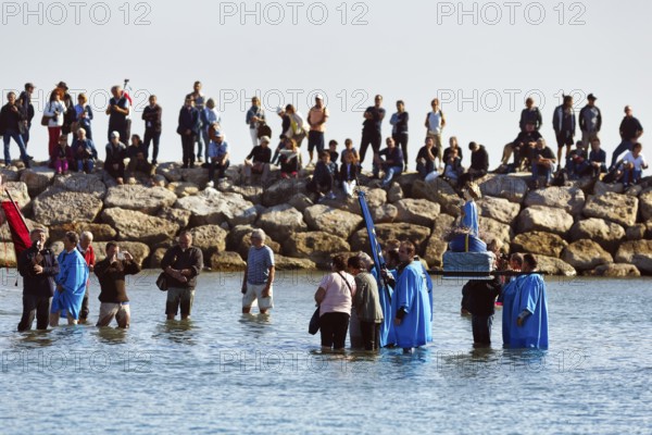 Crowd during pilgrimage, procession by the sea, pilgrims walking through water, statue of the