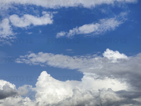 Below white cumulus clouds, centre above stratocumulus above altostratus in front of blue sky,