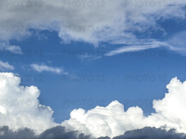 At the bottom of the picture grey white cumulus clouds, at the top altostratus in front of blue