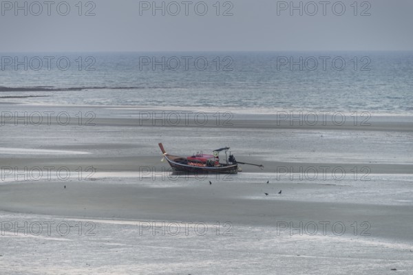 Before sunrise, a lonely longtail boat lies at low tide in the harbour at Sivalai Beach, Koh Mook