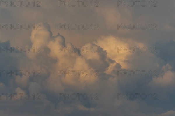 Fluffy clouds fill the sky, tinted by soft oranges and yellows as the sun is setting. The tranquil