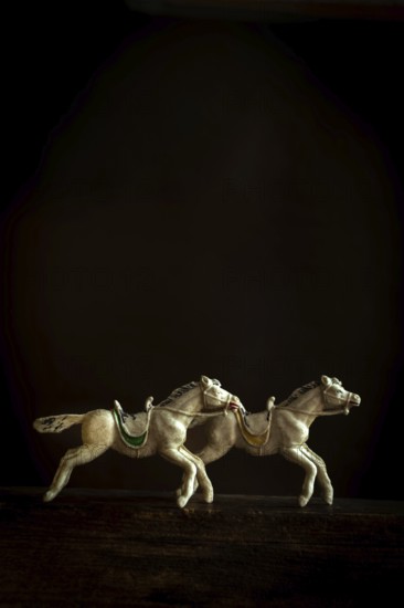 Two intricately designed horse figurines are depicted galloping in sync, creating a sense of