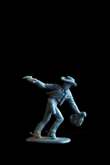 A vibrant blue cowboy action figure strikes a dramatic pose while drawing a weapon, set against a