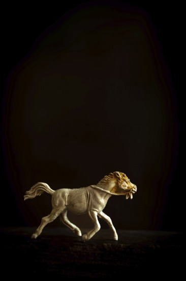 A finely crafted brown wooden horse figure is captured in motion, depicting a galloping stance as