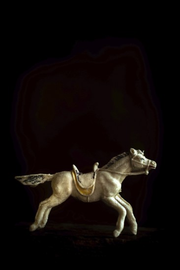 A detailed toy horse is captured in motion, showcasing its intricate design and craftsmanship. The