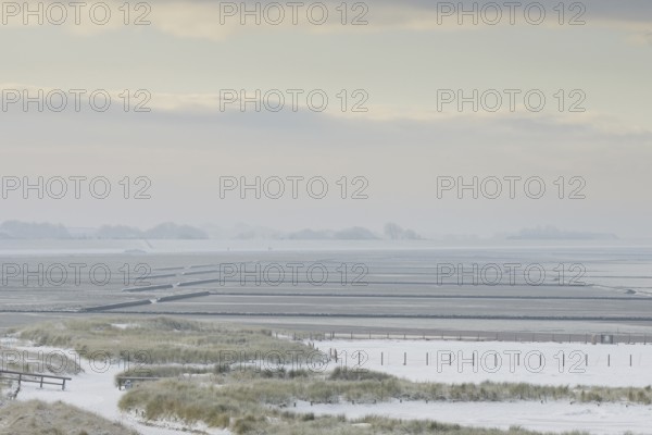 View over the snow-covered dune landscape of Norddeich, Wadden Sea at low tide, North Sea, Lower