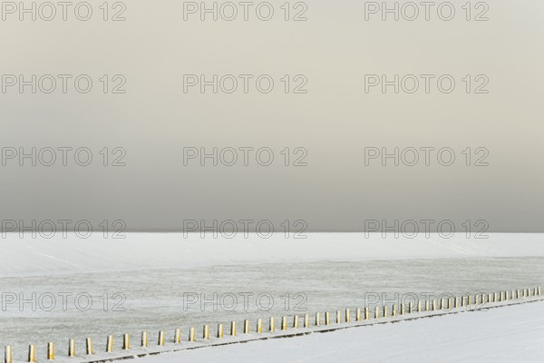 Winter day, onset of winter, snow-covered dyke and boundary piles, North Sea, Norddeich, Lower