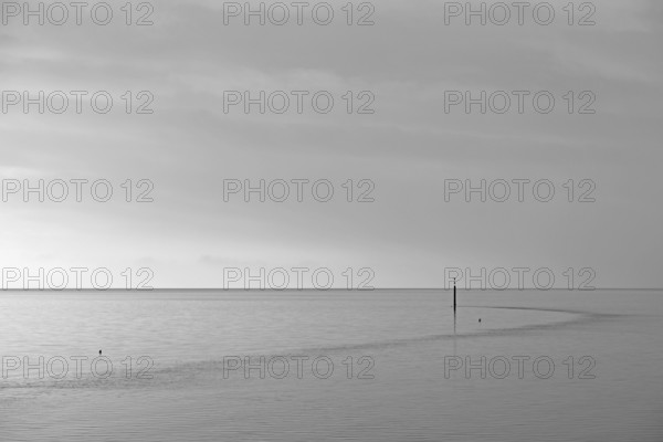Wadden Sea at rising water, stone groyne with sea mark, black and white, North Sea, Norddeich,