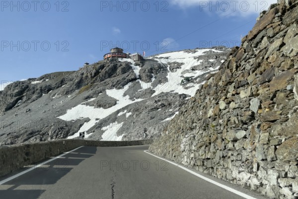 View in front of a narrow bend above the tree line in front of the Stelvio Alpine Pass road to the