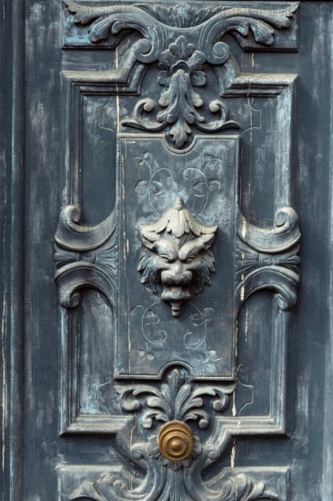 A striking door features detailed carvings and a lion head knocker, blending antique charm with