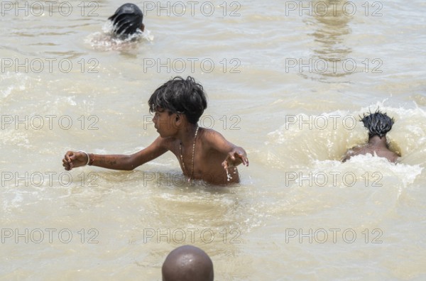 Children bathe in the Brahmaputra River to seek relief from the intense summer heat in Guwahati,