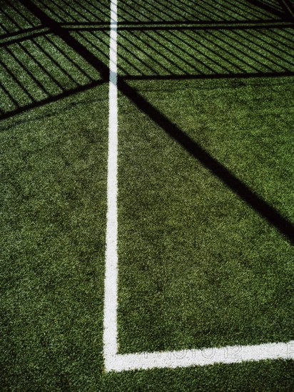 This corner of a sports field features vibrant artificial turf with clear white lines marking the