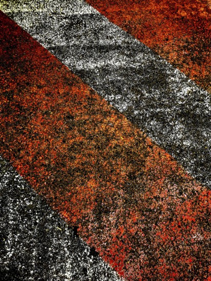 Bold red and black lines create an eye-catching pattern on a rough surface, illuminated by warm