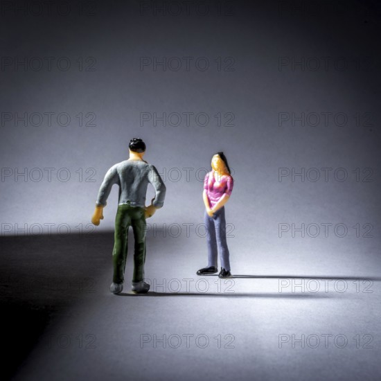 Two small figurines engage in a conversation, with a focus on their body language. The lighting