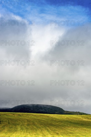 A bright yellow field stretches across the landscape, illuminated by sunlight that peeks through