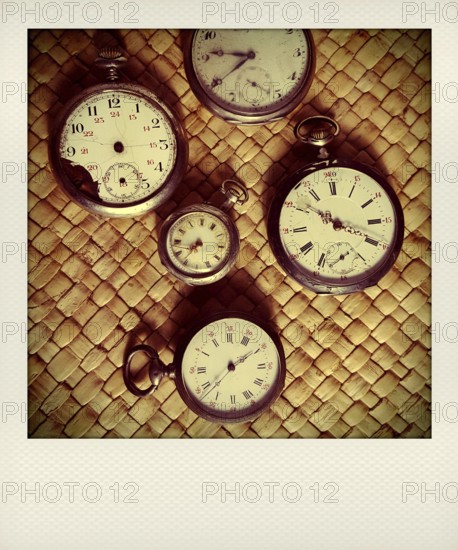 Various vintage stopwatches are displayed closely on a woven surface, highlighting their distinct