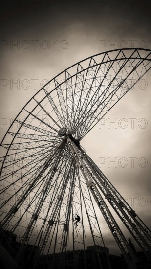 A maintenance worker is seen climbing the structure of a ferris wheel that features vibrant lights.