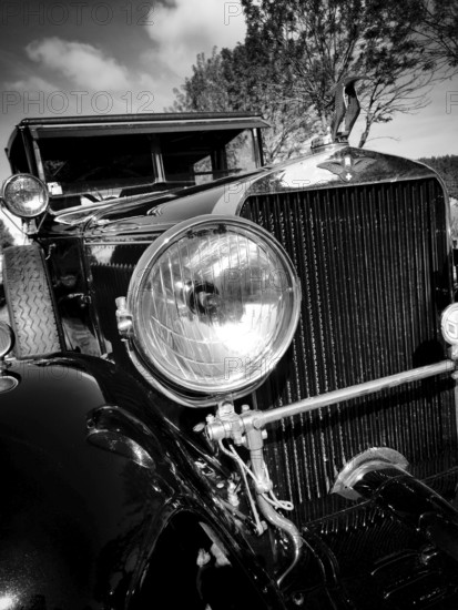 This vintage car displays its polished headlight and elegant grille. The scene captures the beauty