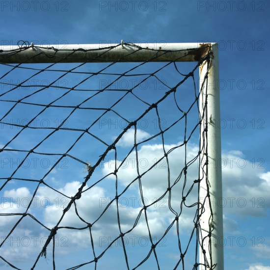 A football goal net is positioned against a cloudy sky, showcasing the intricate details of the