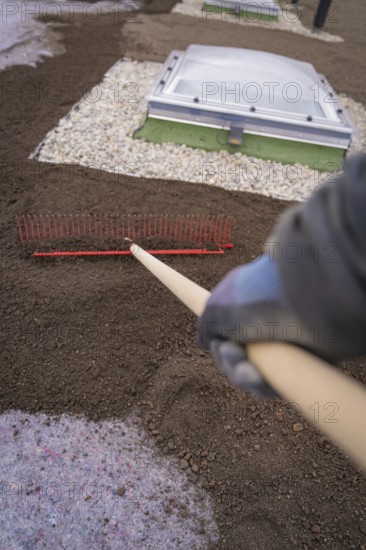 A worker with a rake levels the ground on a roof with gravel beds, roof greening, house