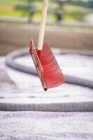 A free-floating red rake in front of a roof with a blurred background in a construction site