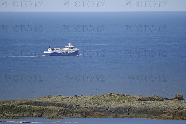 A large fishing vessel navigates the blue sea along the rocky coastline, Sumburgh Head, Shetland